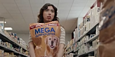 Ratlose Frau mit Hundefutter-Sack im Supermarkt