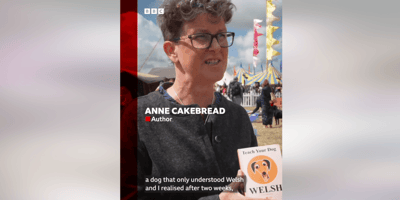 Anne Cakebread holding a copy of her book "How to teach your dog Welsh"