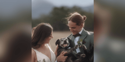 Couple holding black dog on their wedding day