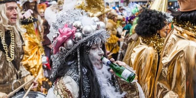 Karnevals-Teilnehmer trinkt aus einer Flasche