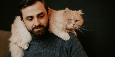 Man with long-haired ginger cat on shoulders