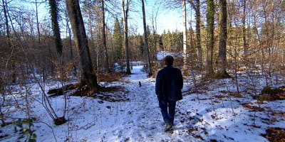 Man loopt door de besneeuwde natuurbegraafplaats