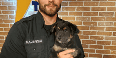 Zac, bénévole du refuge, avec un chien dans les bras