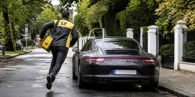 Postbote rennt auf parkenden Porsche zu