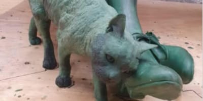 Statue of cat by woman's feet