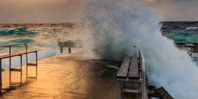 Welle bricht sich an einer Kaimauer