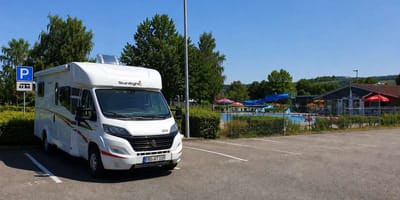 Wohnmobil auf Parkplatz neben Freibad