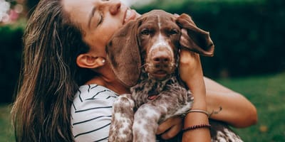 Woman happily cuddling dog