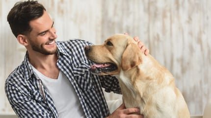 junger mann lacht und streichelt hund
