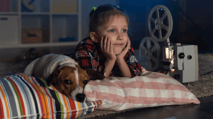 jack russell and young girl watching movie on a bed