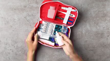 A person reaching inside a first aid kit