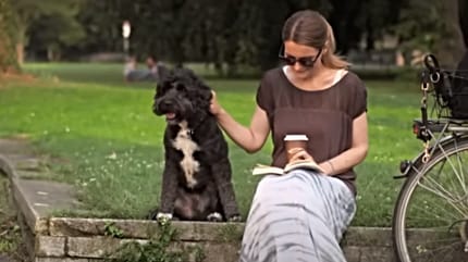Frau liest und streichelt Hund