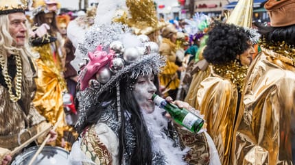 Un participant au carnaval boit à la bouteille