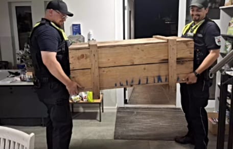 2 Männer tragen große Holzkiste
