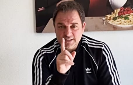 Rütter sitzend mit erhobenem Zeigefinger