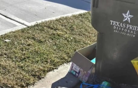 Mülltonne mit Abfallsäcken daneben