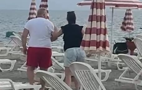 Frau führt Mann am Strand weg