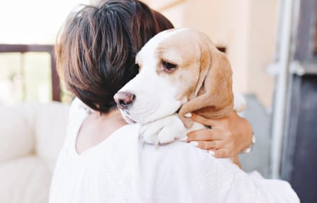 Frau hält Hund fest im Arm