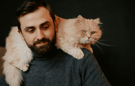 Man with long-haired ginger cat on shoulders