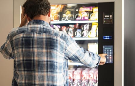 Mann vor einem Snackautomaten