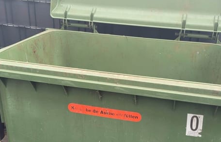 Offenstehender grüner Müllcontainer