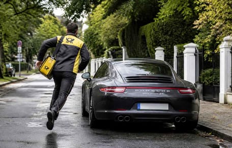 Postbote rennt auf parkenden Porsche zu