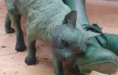 Statue of cat by woman's feet