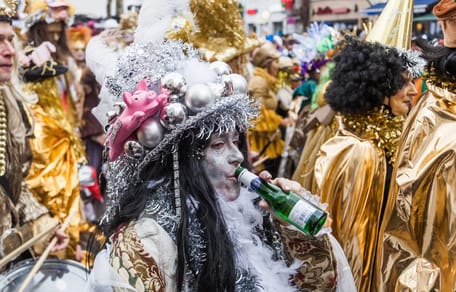 Un partecipante al carnevale beve dalla bottiglia