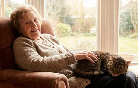 Eine ältere Dame kuschelt glücklich mit ihrer Katze