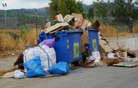 Volle Müllcontainer mit einer Tasche daneben
