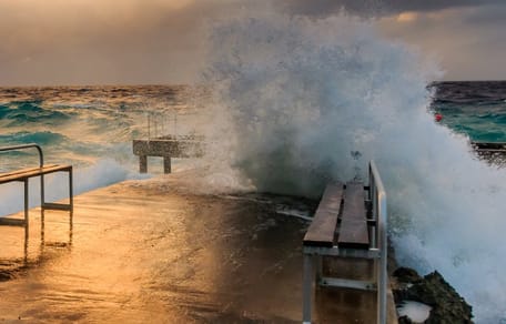 Welle bricht sich an einer Kaimauer