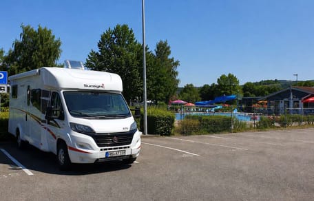 Wohnmobil auf Parkplatz neben Freibad