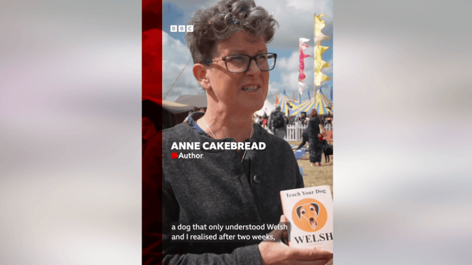 Anne Cakebread holding a copy of her book "How to teach your dog Welsh"
