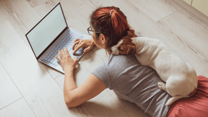 Frau im Homeoffice mit einem Jack Russell, der auf ihrem Rücken ruht