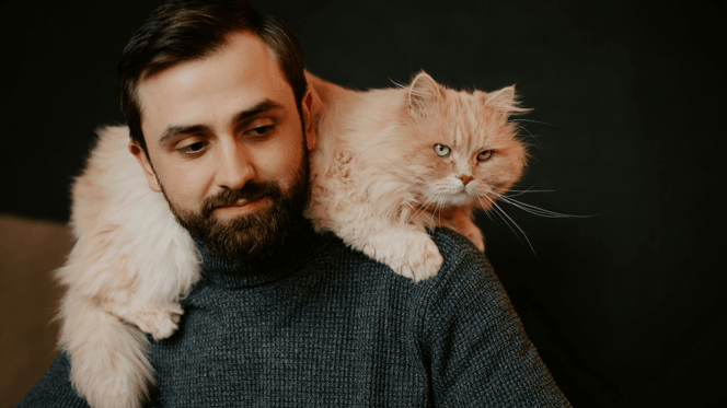 Man with long-haired ginger cat on shoulders