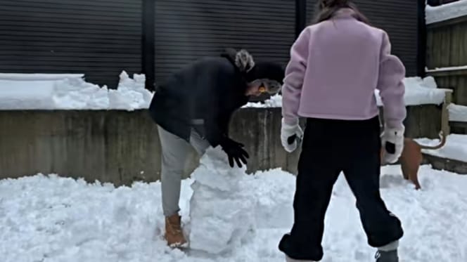 Paar baut einen Schneemann im Garten