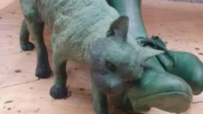 Statue of cat by woman's feet