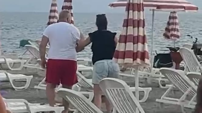 Una donna allontana un uomo sulla spiaggia