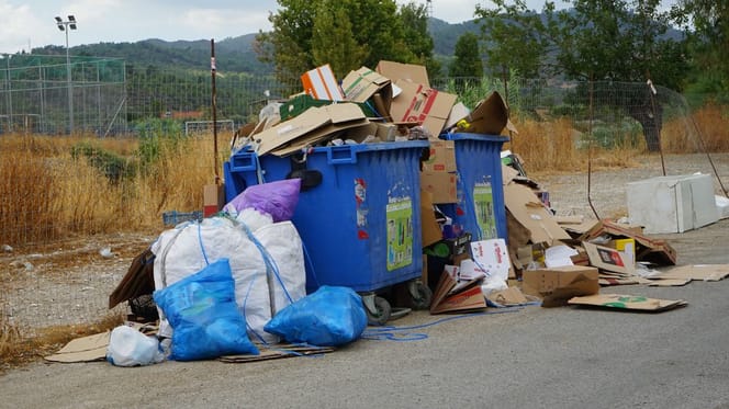 Volle Müllcontainer mit einer Tasche daneben