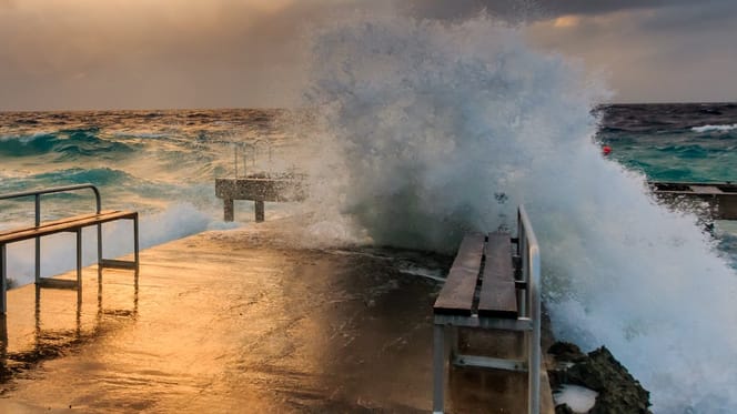 Welle bricht sich an einer Kaimauer