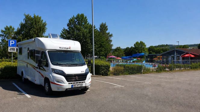 Wohnmobil auf Parkplatz neben Freibad