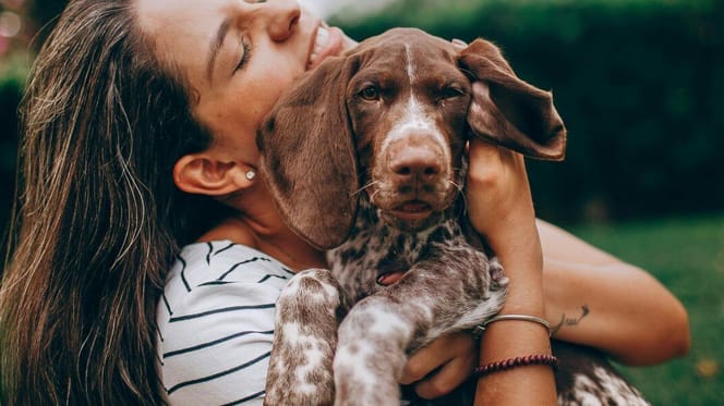 Woman happily cuddling dog