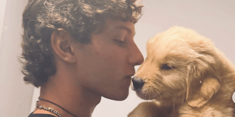 Kimi Antonelli abbraccia Lola Bunny, una cucciola di Golden Retriever, durante una visita a un allevamento
