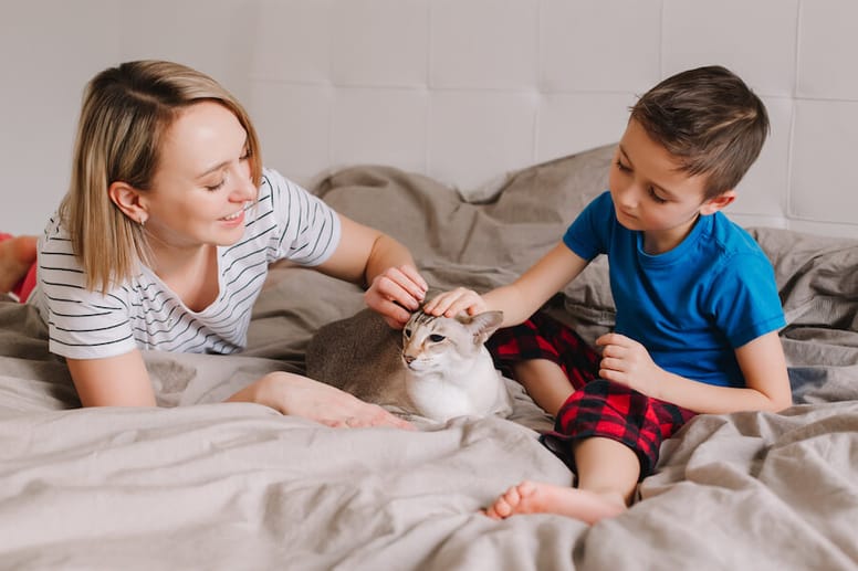 mujer niño y gato en la cama