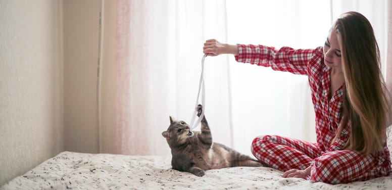 mujer juega con gato listón